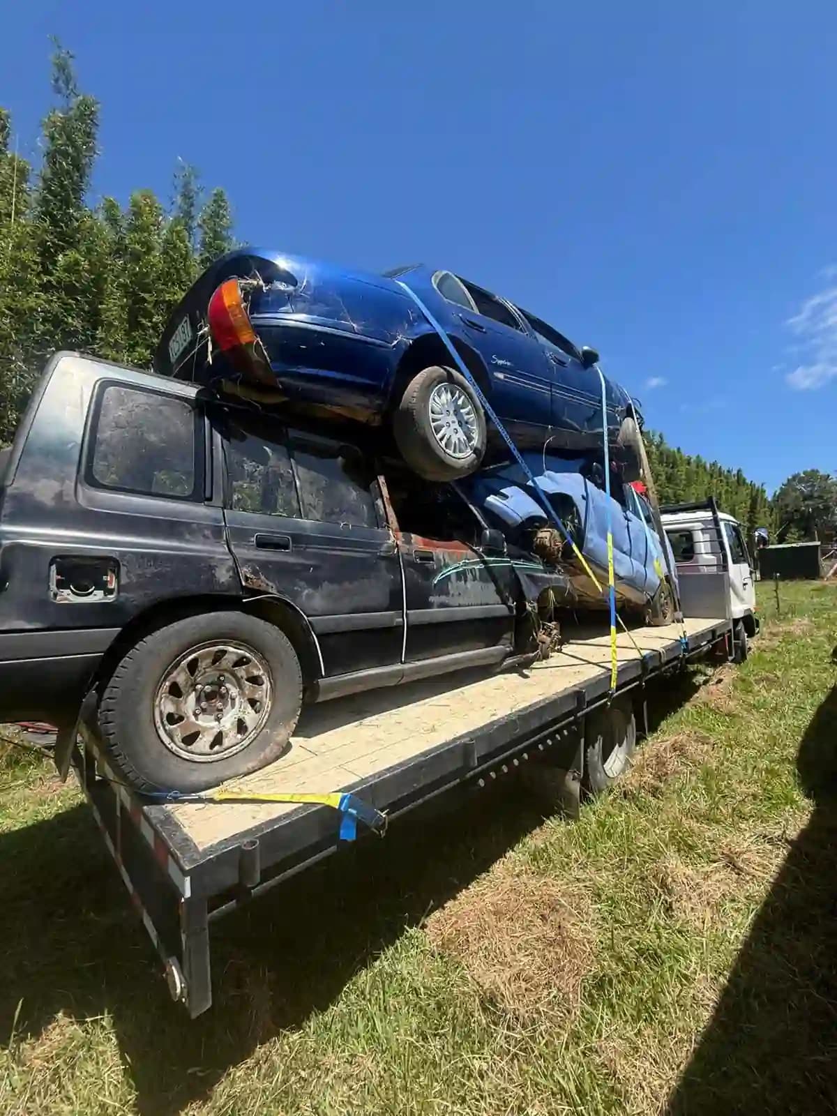 Apex Car Removal team member inspecting an old station wagon parked near the Tairua boat ramp
