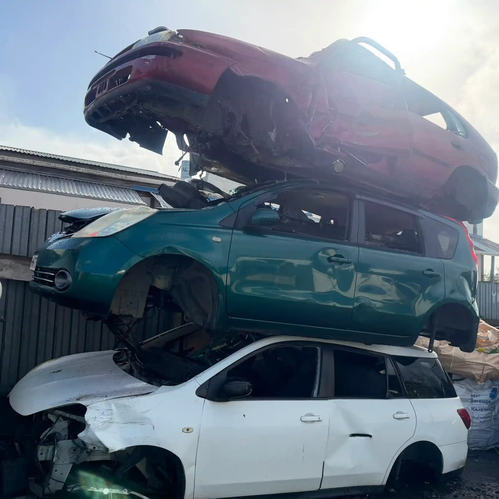 Apex Car Removal flatbed tow truck loading an old ute on a rural driveway near kiwifruit orchards outside Te Puke